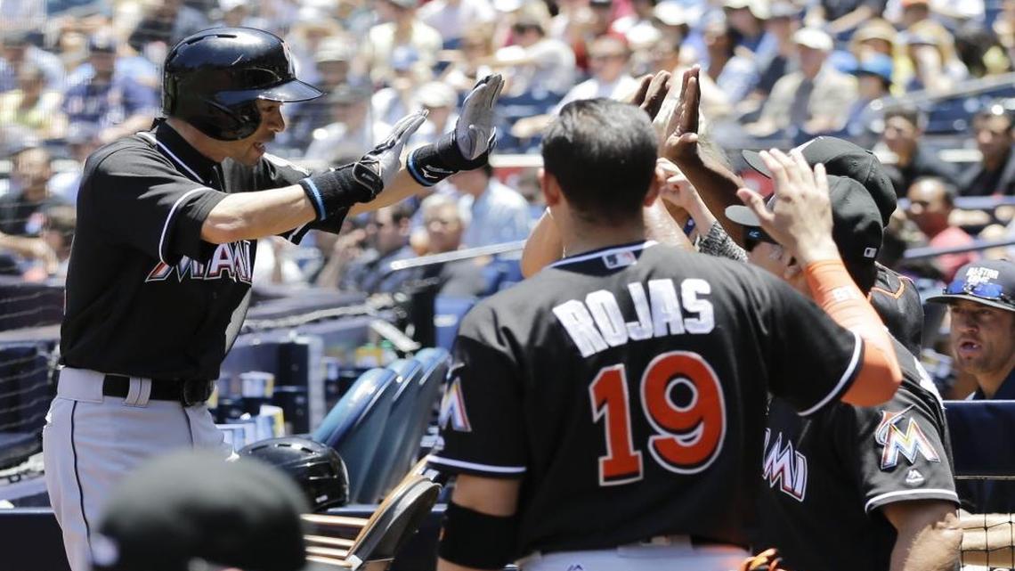 Miami Marlins' Ichiro Suzuki, left, is greeted at the dugout after scoring on an RBI single by Christian Yelich during the first inning of a baseball game against the San Diego Padres Wed., June 15, 2016, in San Diego. With the single Suzuki hit to get on base in the first inning, his combined career hits in Japan and the major leagues ties Pete Rose's mark of 4,256, the record in the majors.