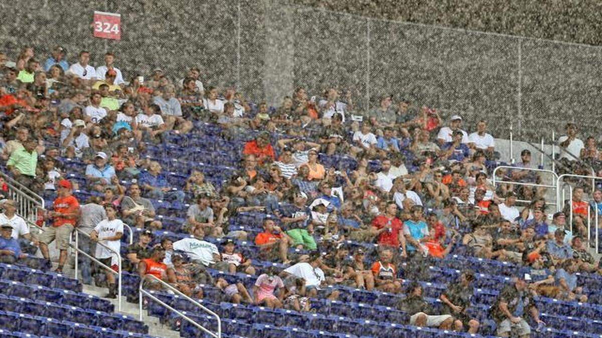 
Fans get wet as a rain storm moved over the stadium with the roof open as the Miami Marlins played the Atlanta Braves on opening day at Marlins Park in Miami, Florida, April 6, 2015.
