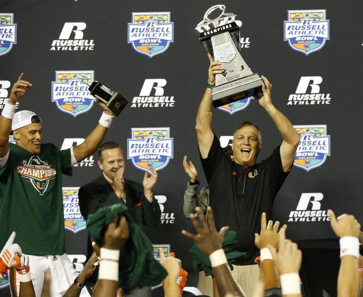 Miami Hurricanes head coach Mark Richt raises the Championship trophy after the University of Miami defeats West Virginia Mountaineers at the Russell Athletic Bowl in Orlando Wed., Dec. 28, 2016.