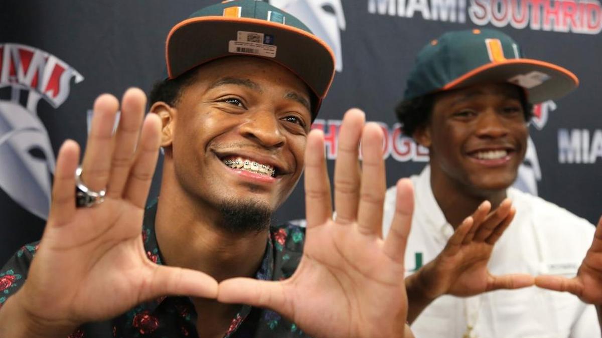 Teammates Mark Pope, left, and Daquris Wiggins, gesture after signing with the Miami Hurricanes NCAA college football team at Miami Southridge High in Miami, Fla., Wednesday, Dec. 20, 2017.
