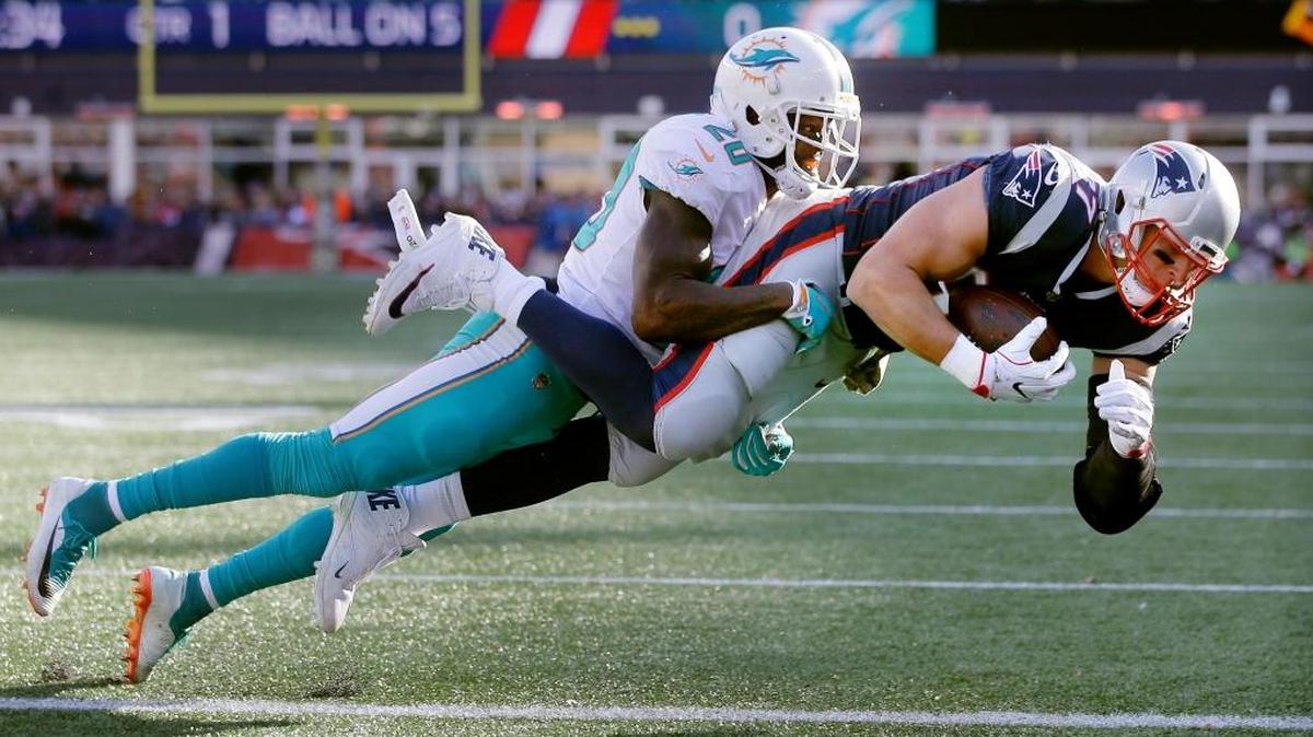 New England Patriots tight end Rob Gronkowski, right, scores a touchdown with Miami Dolphins safety Reshad Jones on his back during the first half of an NFL football game, Sun., Nov. 26, 2017, in Foxborough, Mass.