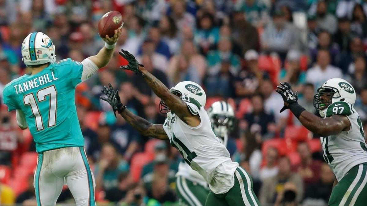 Miami Dolphins quarterback Ryan Tannehill, left, tries to get a pass away under pressure against the New York Jets at Wembley Stadium in London, Sunday, Oct. 4, 2015.