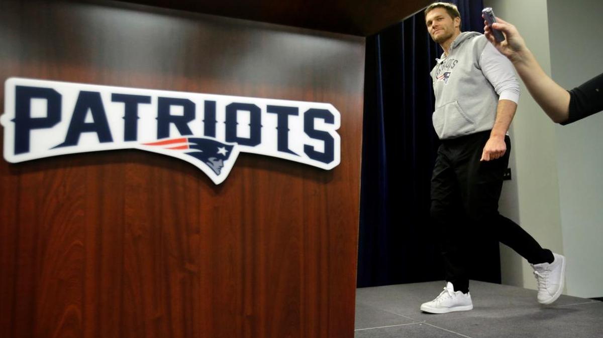 New England Patriots quarterback Tom Brady walks past a reporter with a microphone, right, as he approaches the podium to take questions from members of the media before a scheduled NFL football practice, Thurs., Jan. 5, 2017, in Foxborough, Mass.