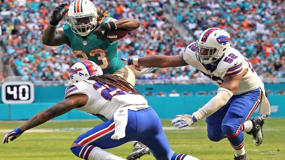 Miami Dolphins Jay Ajayi runs the ball in the fourth quarter to help set up a touchdown as Buffalo Bills Ronald Darby, 28, and Preston Brown, 52, defend at Hard Rock Stadium in Miami Gardens, Florida on Sun., Oct. 23, 2016.