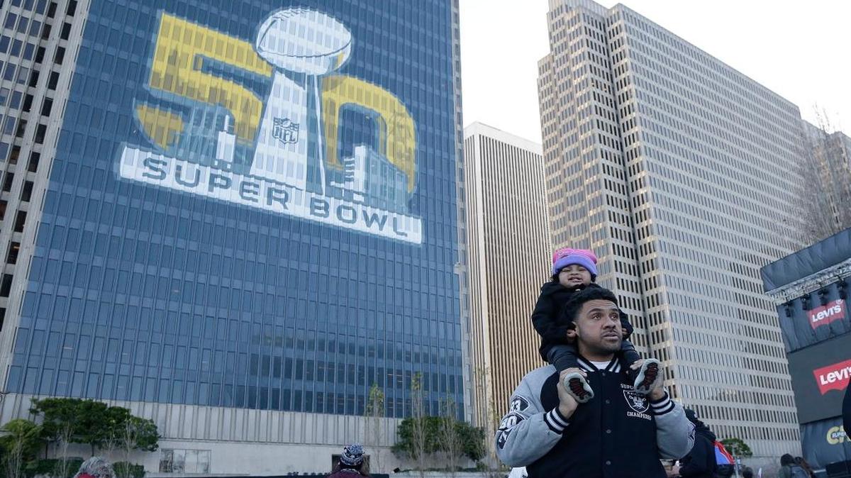 Fans walk below a sign at Super Bowl City in San Francisco, Sunday, Jan. 31, 2016. The Denver Broncos will play the Carolina Panthers in Super Bowl 50 Sunday, Feb. 7, 2016.