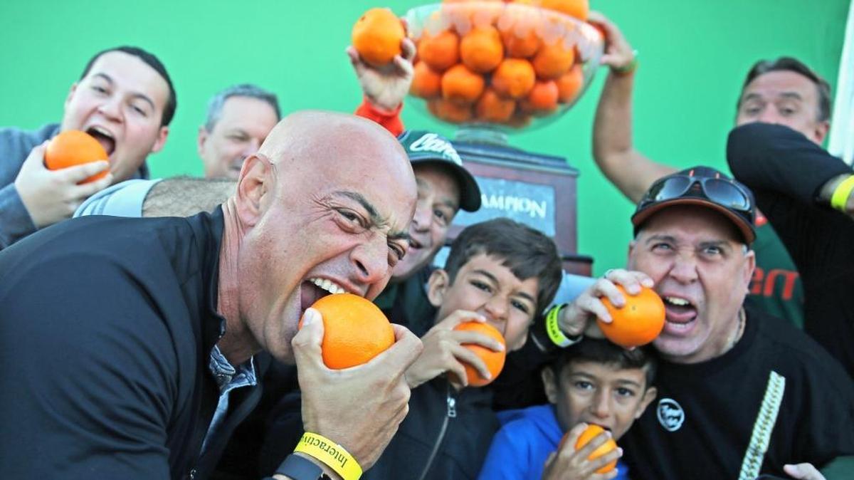 Miami Hurricanes fan Ash Boutros bites an orange in the fan festival with friends and family as the Canes prepare to play the Wisconsin Badgers in the 2017 Capital One Orange Bowl at Hard Rock Stadium in Miami Gardens on December 30, 2017.
