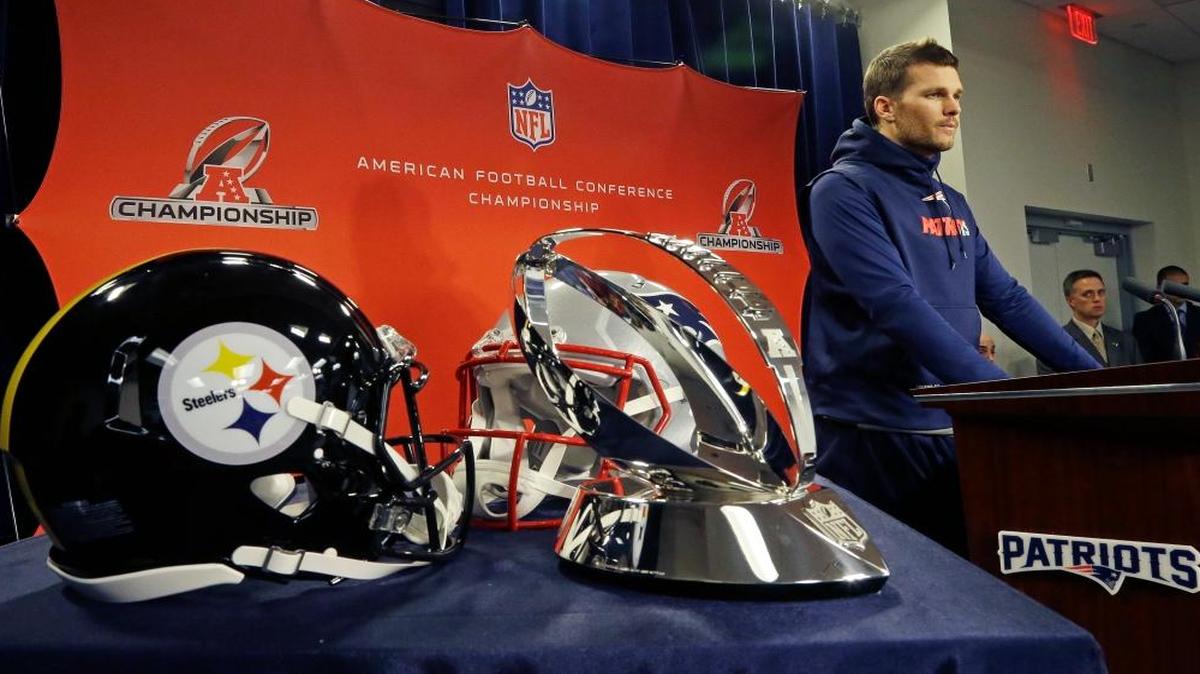 The AFC championship trophy and Steelers and Patriots helmets are displayed at left as New England Patriots quarterback Tom Brady speaks to media before an NFL football team practice, Wed., Jan.18, 2017, in Foxborough, Mass. The Patriots will host the Pittsburgh Steelers in the AFC championship game on Sunday.