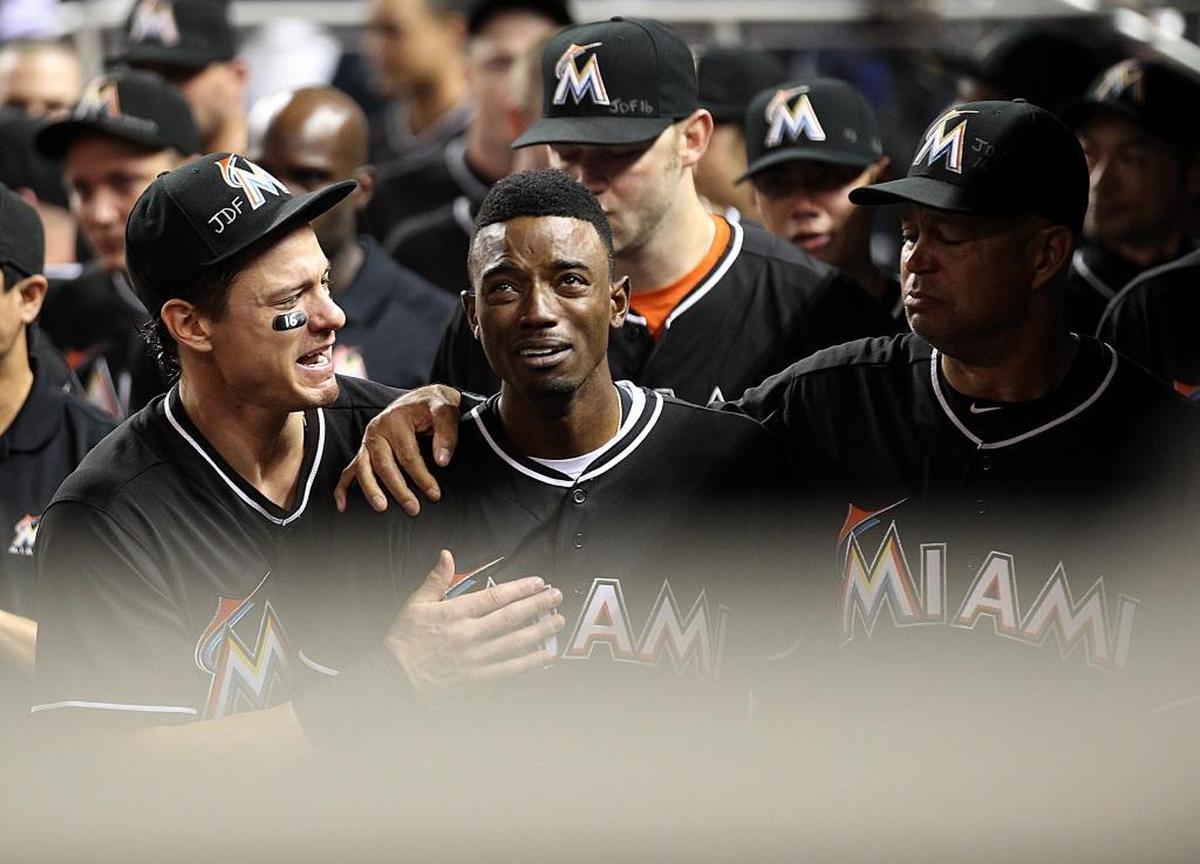 Miami Marlins' Dee Gordon (9), center, gets consoled by Derek Dietrich (32), left, after hitting a home run during the first inning of a baseball game against the New York Mets at Marlins Park the day after pitcher Jose Fernandez was killed in a boat crash.