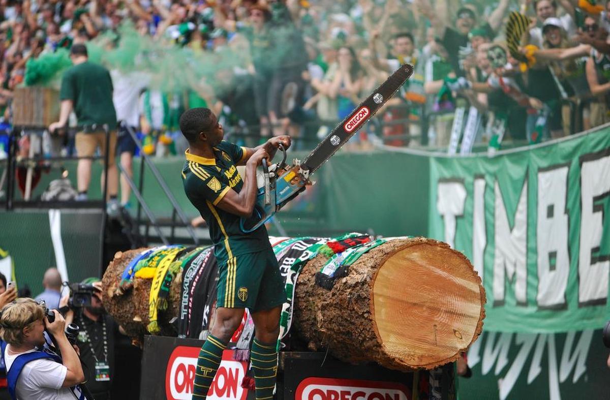 Portland Timbers’ Fanendo Adi (9) celebrates his goal by jumping the fence and holding up the chainsaw for the fans during the second half of an MLS Soccer game in Portland, Ore., Sunday June 28, 2015. Portland beat Seattle 4-1.