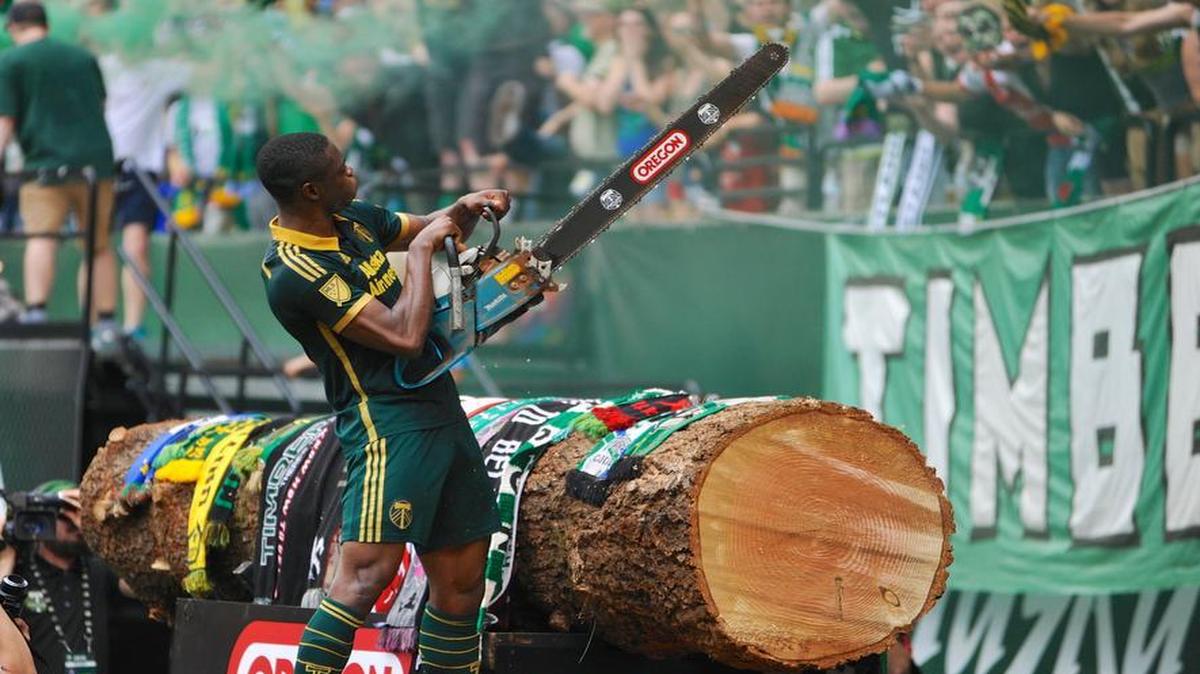 Portland Timbers’ Fanendo Adi (9) celebrates his goal by jumping the fence and holding up the chainsaw for the fans during the second half of an MLS Soccer game in Portland, Ore., Sunday June 28, 2015. Portland beat Seattle 4-1.