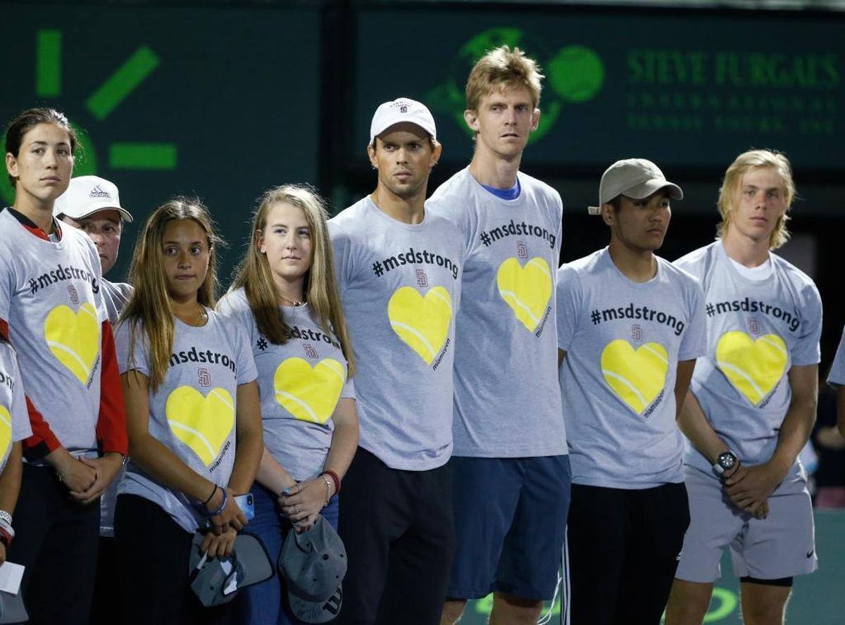 Players Mike Bryan, center left, and Kevin Anderson, center right, stand with members of the Marjory Stoneman Douglas High School tennis team during a ceremony honoring the victims of the school shooting in February, before the start of the night session of the Miami Open, Saturday, March 24, 2018, in Key Biscayne, Fla.