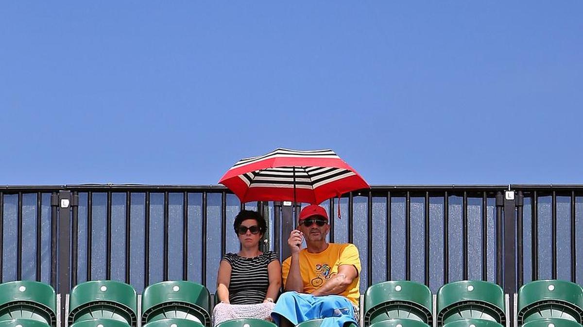 A couple seeks shade at the top of the Stadium court during a match at the Miami Open at the Crandon Park Tennis Center on Key Biscayne in March 2017.