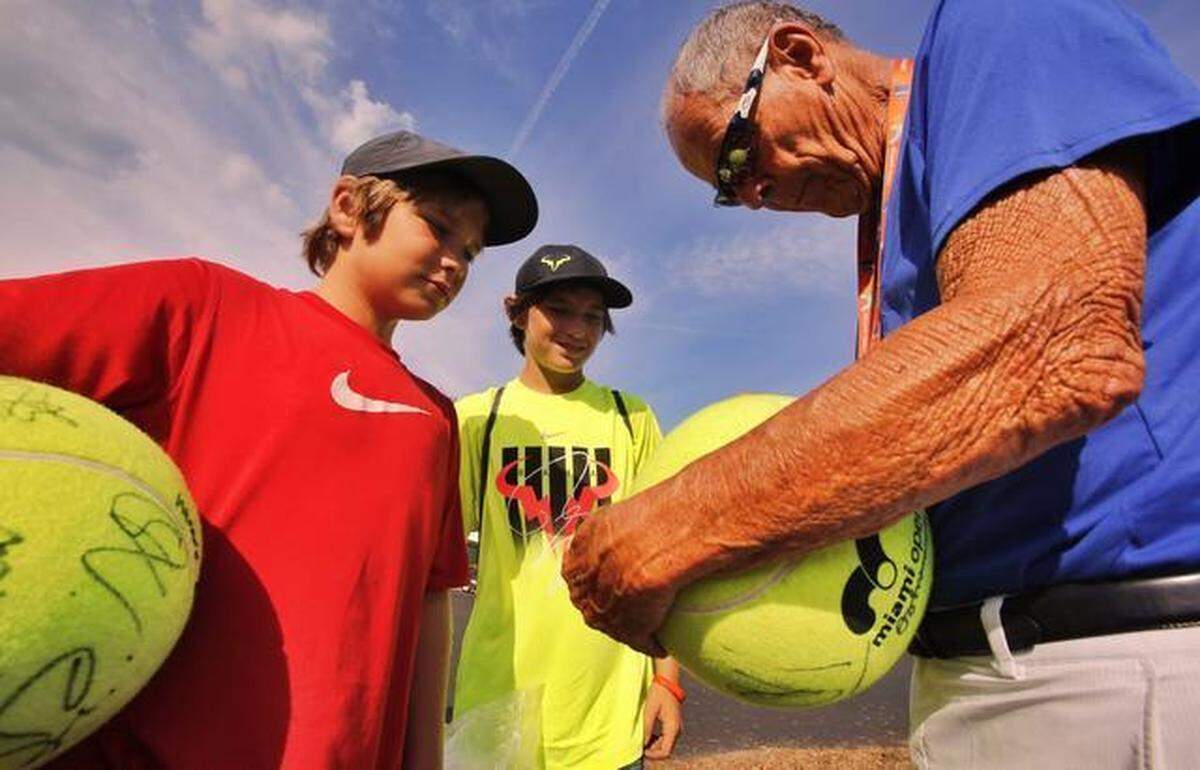Legendary tennis coach Nick Bollettieri signs balls for brothers Matthew Pollak, 10, and John Pollak, 13, on Monday, March 23, 2015 at the Miami Open in Key Biscayne.