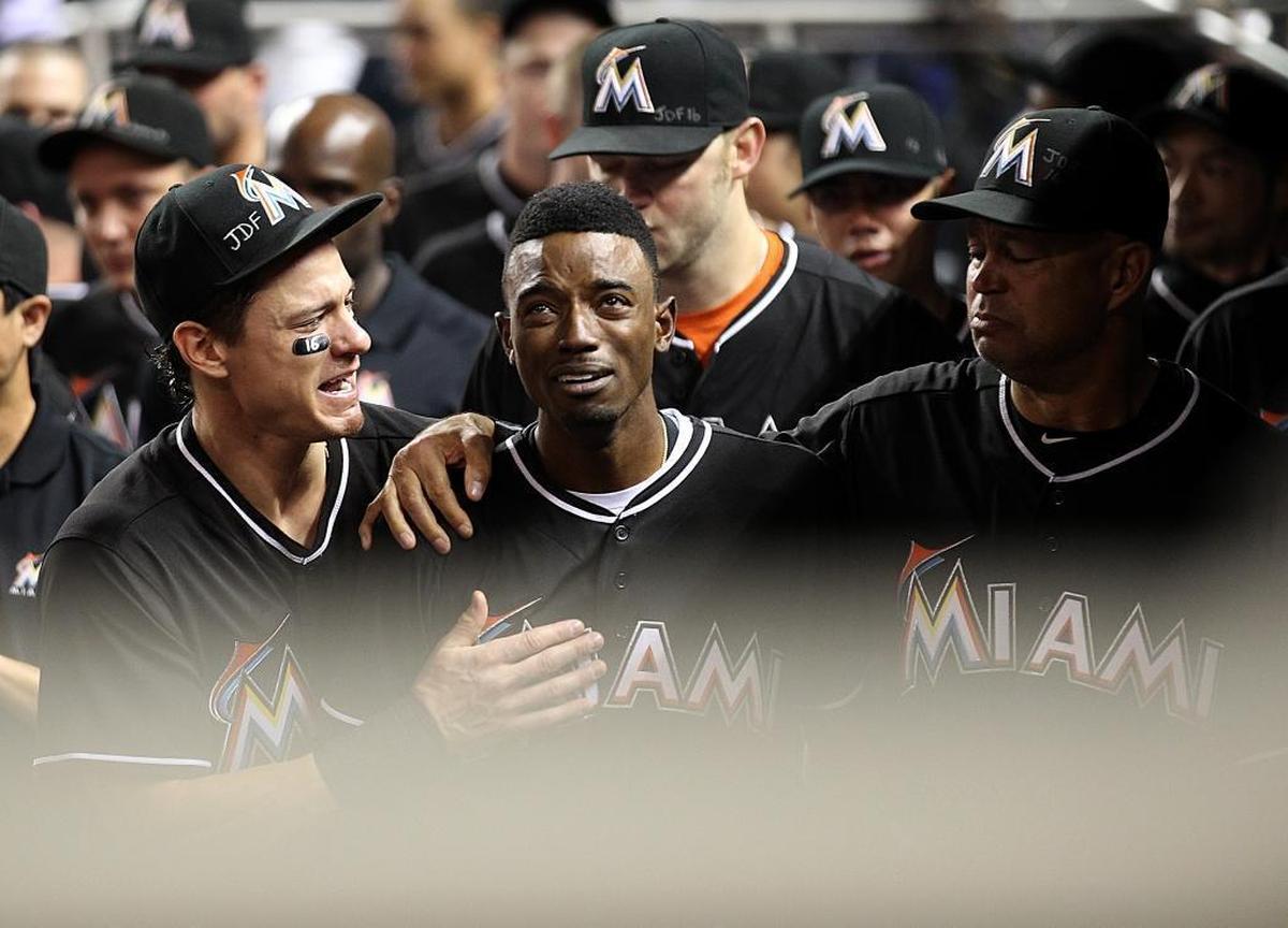 Miami Marlins' Dee Gordon, center, gets consoled by Derek Dietrich, left, after hitting a home run the day after Jose Fernandez’s death, Monday, Sept. 26, 2016.