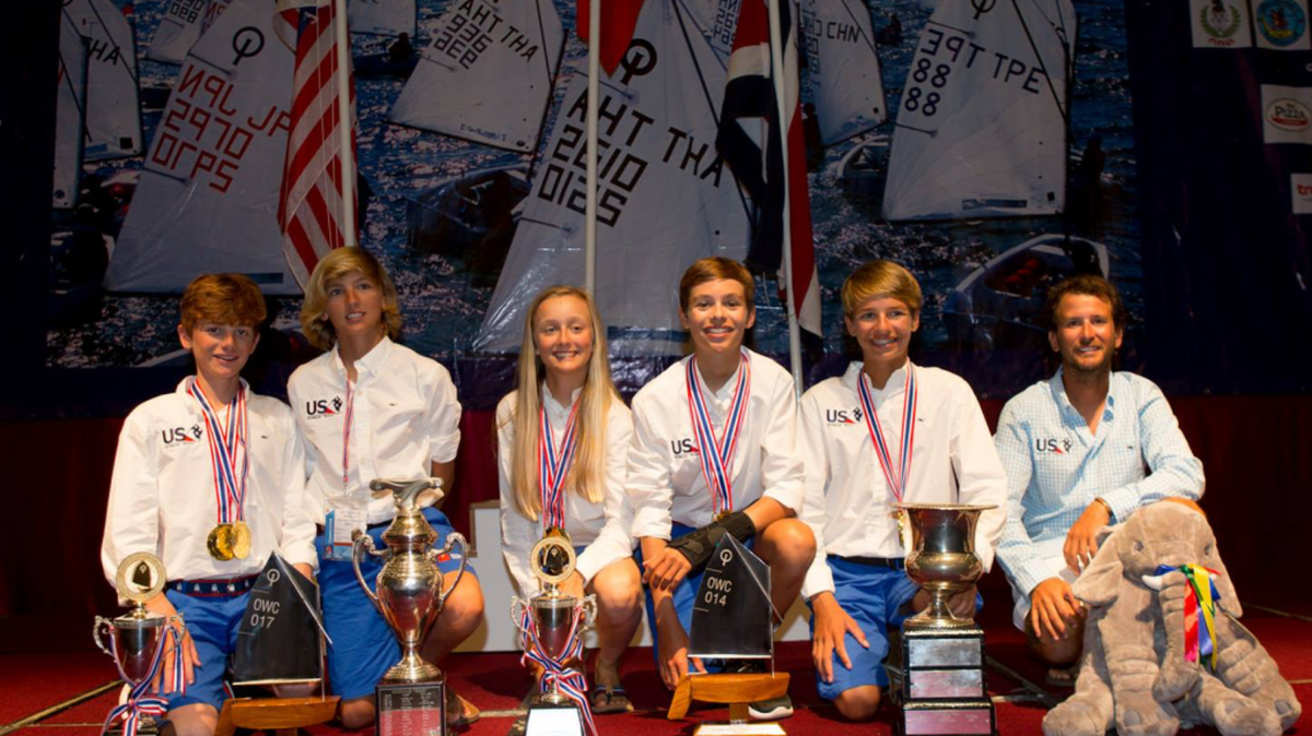 Representing Team USA, (from left) Liam O’Keefe, Stephan Baker, Charlotte Leigh, Mitchell Callahan, and Justin Callahan display their impressive haul of medals and trophies they won during the Optimist World Sailing Championships in Thailand. This is the first time all five American team qualifiers are members of the same club (Coral Reef Yacht Club in Coconut Grove). Also pictured is Coach Lior Lavie.