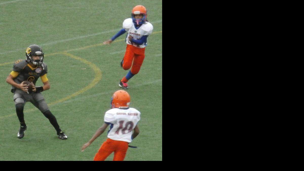 
Quarterback Ari Arteaga (6) of the Kendall Boys & Girls Club Kolts looks for running room against a tough South Kendall Gators defense in a 12U (130 pound) semifinal of the Miami Xtreme Youth Football League at Ted Hendricks Stadium at Milander Park in Hialeah. Also pictured includes Ali Skipper (10) of the Gators.
